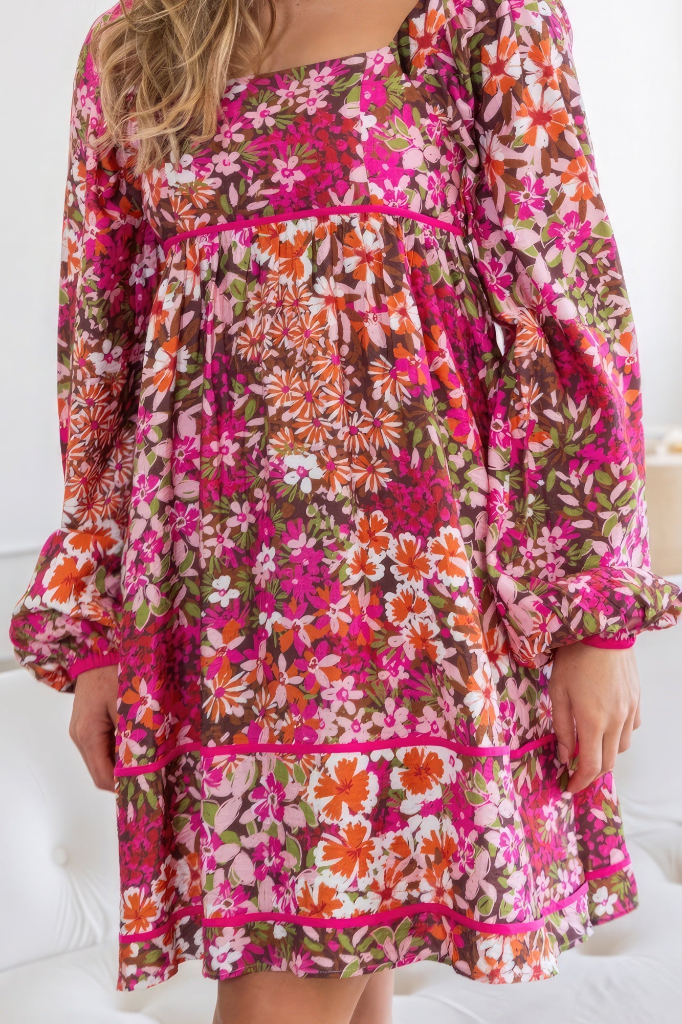 Introducing The Alyssa, a charming and stylish piece. This delightful dress features a square neckline, a tiered silhouette, and a captivating floral pattern in a rich dark pink hue. It has a smocked back bodice, long sleeves and functional side pockets. Immerse yourself in the luxurious blend of 75% rayon and 25% nylon, offering a lightweight and comfortable feel. Perfect for various occasions, this mini dress seamlessly transitions from casual outings to semi-formal events.