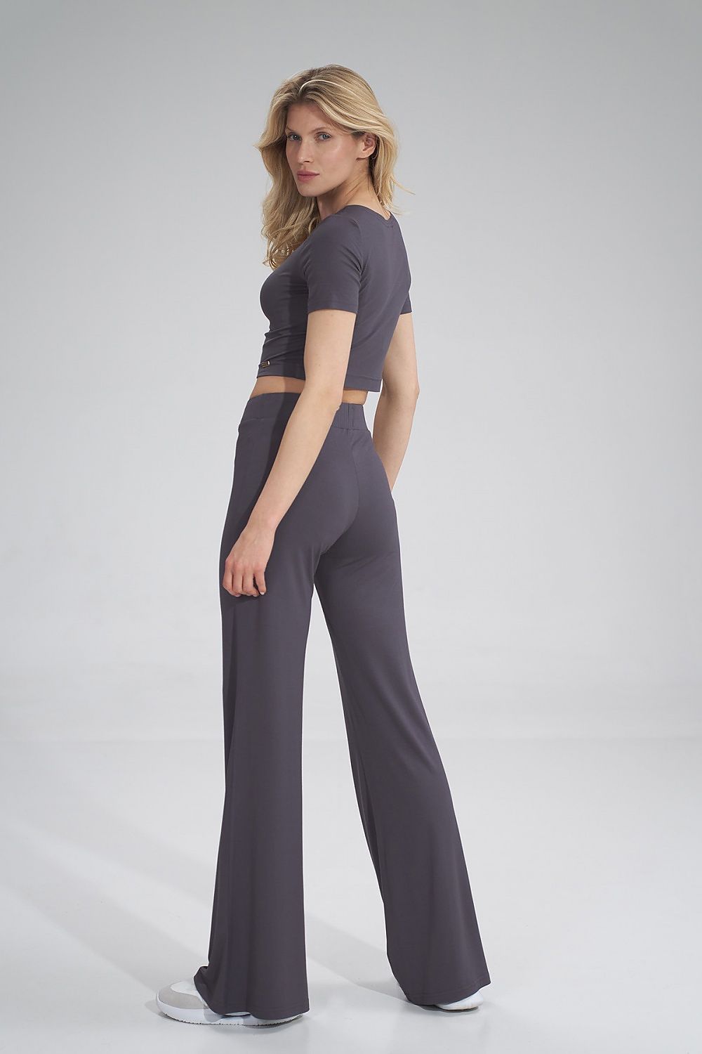 The Raven Pants is a long bell-bottom pair of trousers with a wide elastic waistband, no pockets and no zipper. It goes hand in hand with The Raven Crop Top. Colour: gray.