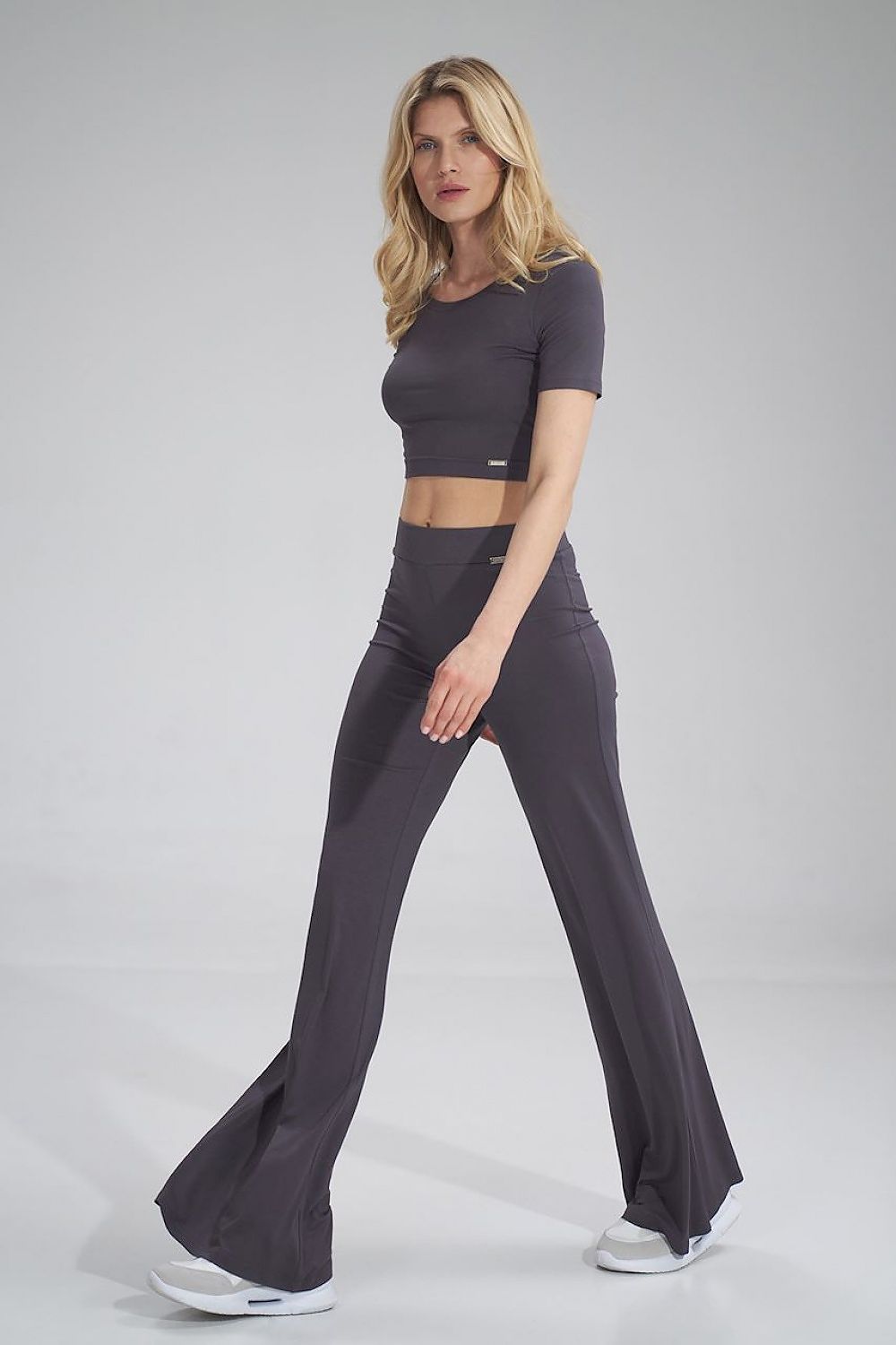 The Raven Pants is a long bell-bottom pair of trousers with a wide elastic waistband, no pockets and no zipper. It goes hand in hand with The Raven Crop Top. Colour: gray.