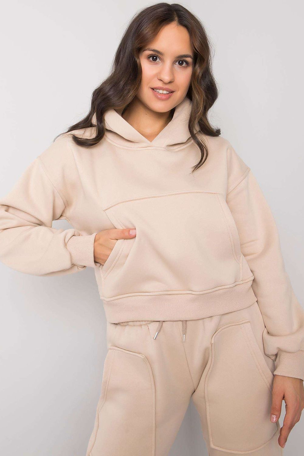 A set consisting of a beige hooded sweatshirt with long sleeves and a pocket on the front and sweatpants with patch pockets and tie at waist.