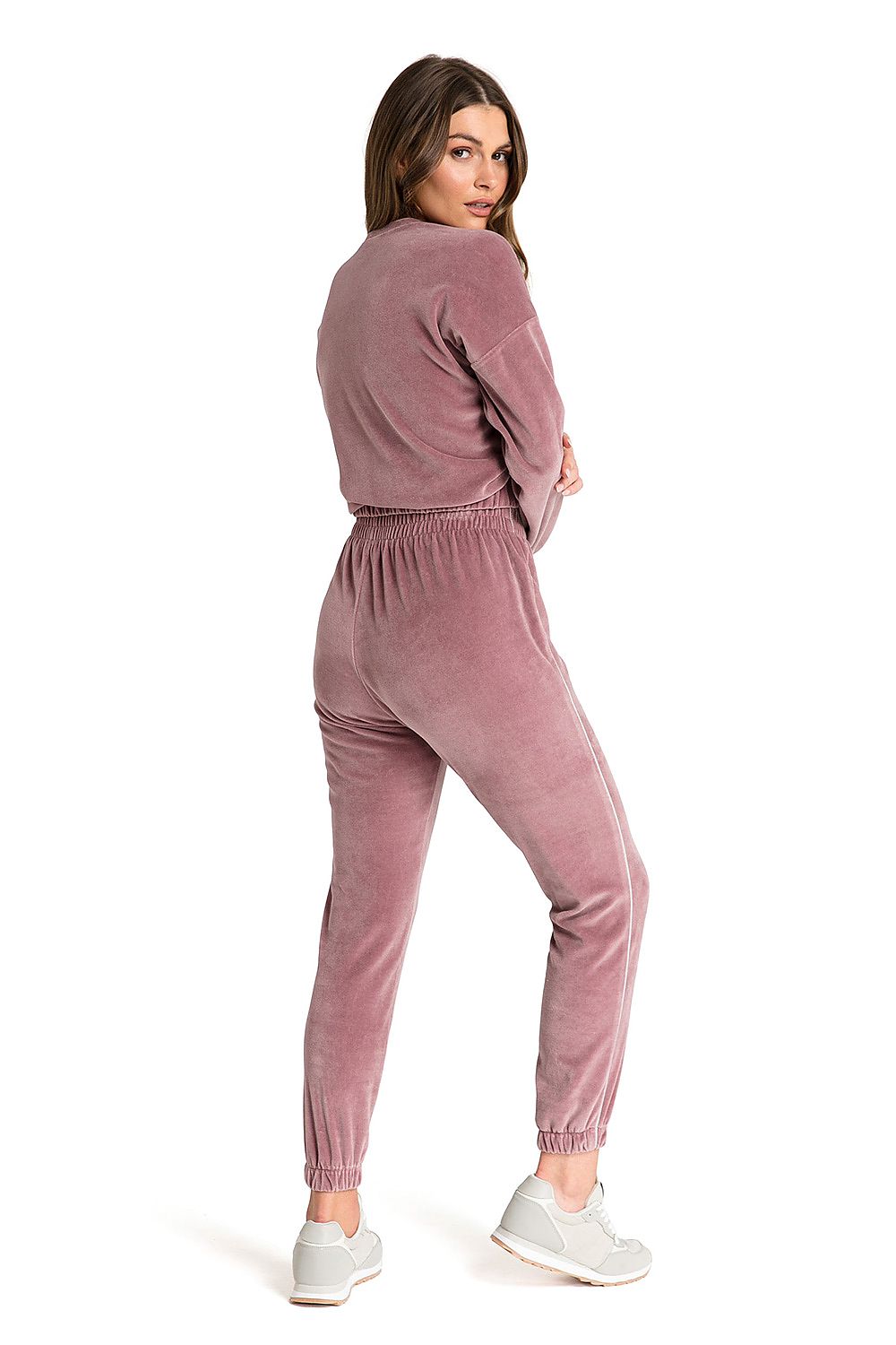 Velour pink sweatpants with slim legs ending in elastic and decorative piping on the sides.