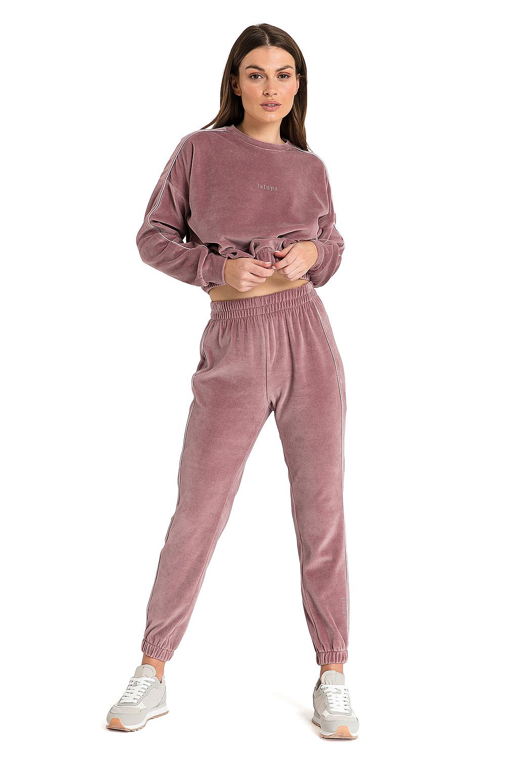 Velour pink sweatpants with slim legs ending in elastic and decorative piping on the sides.
