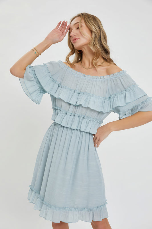 The Kayla is a relaxed-fit, bohemian-style dress that effortlessly combines elegance and comfort. This off-shoulder, short-sleeve dress features an elastic waist, a ruffle bottom, and a feminine silhouette. Crafted from 100% polyester, The Kayla is both soft and lightweight. This misty blue dress is ideal for casual weddings, outdoor gatherings and beach vacations.