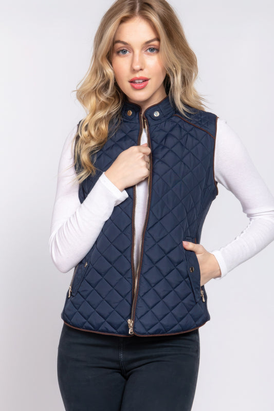 The Britney is our suede piping quilted padding vest. Crafted from 100% polyester, this vest is perfect for layering over sweaters or long sleeves. It features front pockets and side ribbing for added texture and style. Fabric: Made from 100% polyester. Colour: Navy.