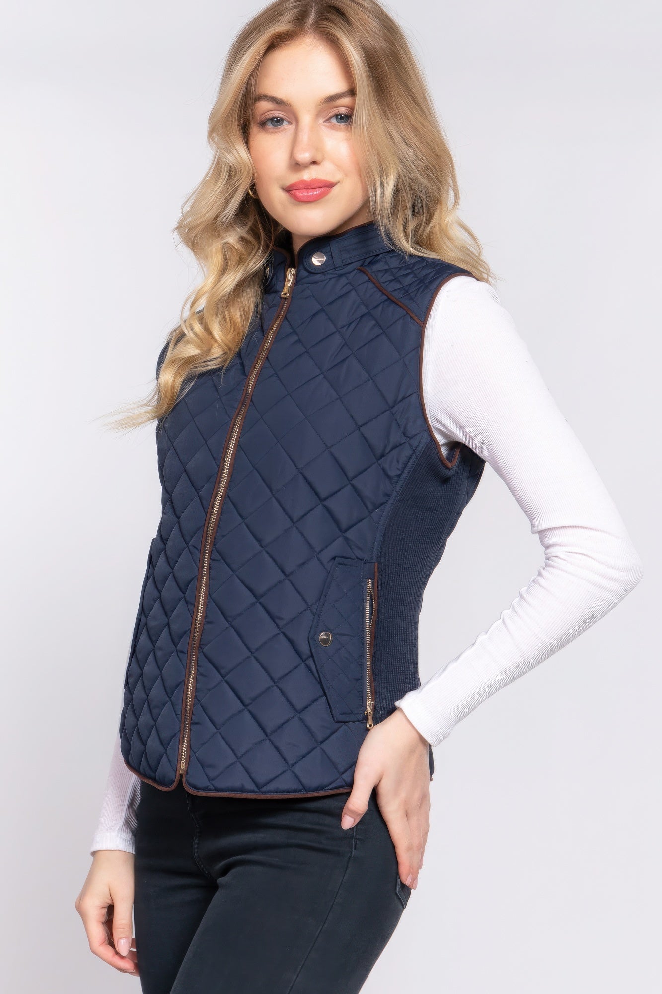 The Britney is our suede piping quilted padding vest. Crafted from 100% polyester, this vest is perfect for layering over sweaters or long sleeves. It features front pockets and side ribbing for added texture and style. Fabric: Made from 100% polyester. Colour: Navy.