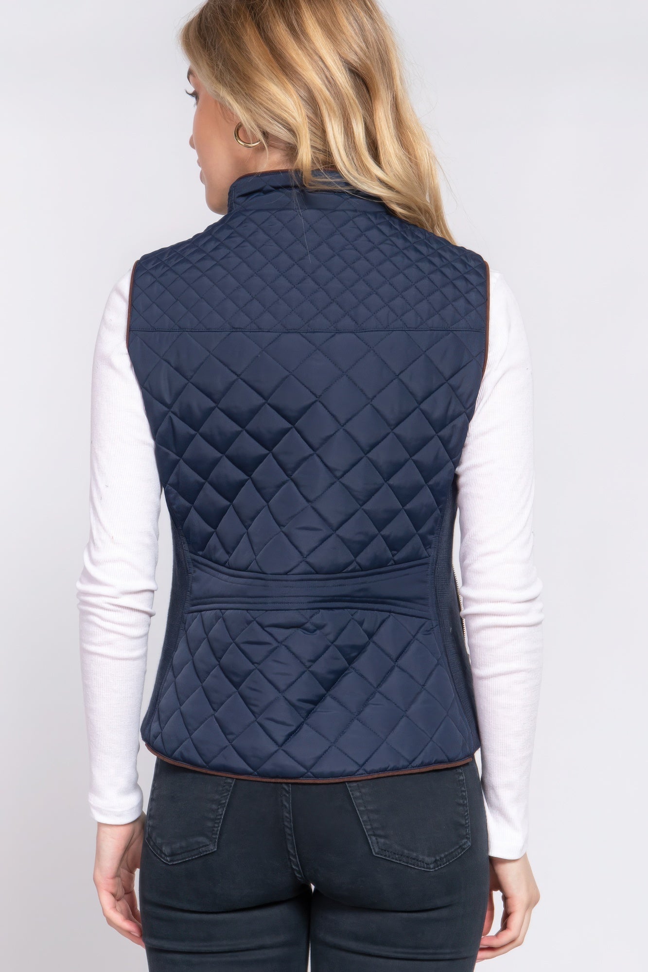 The Britney is our suede piping quilted padding vest. Crafted from 100% polyester, this vest is perfect for layering over sweaters or long sleeves. It features front pockets and side ribbing for added texture and style. Fabric: Made from 100% polyester. Colour: Navy.