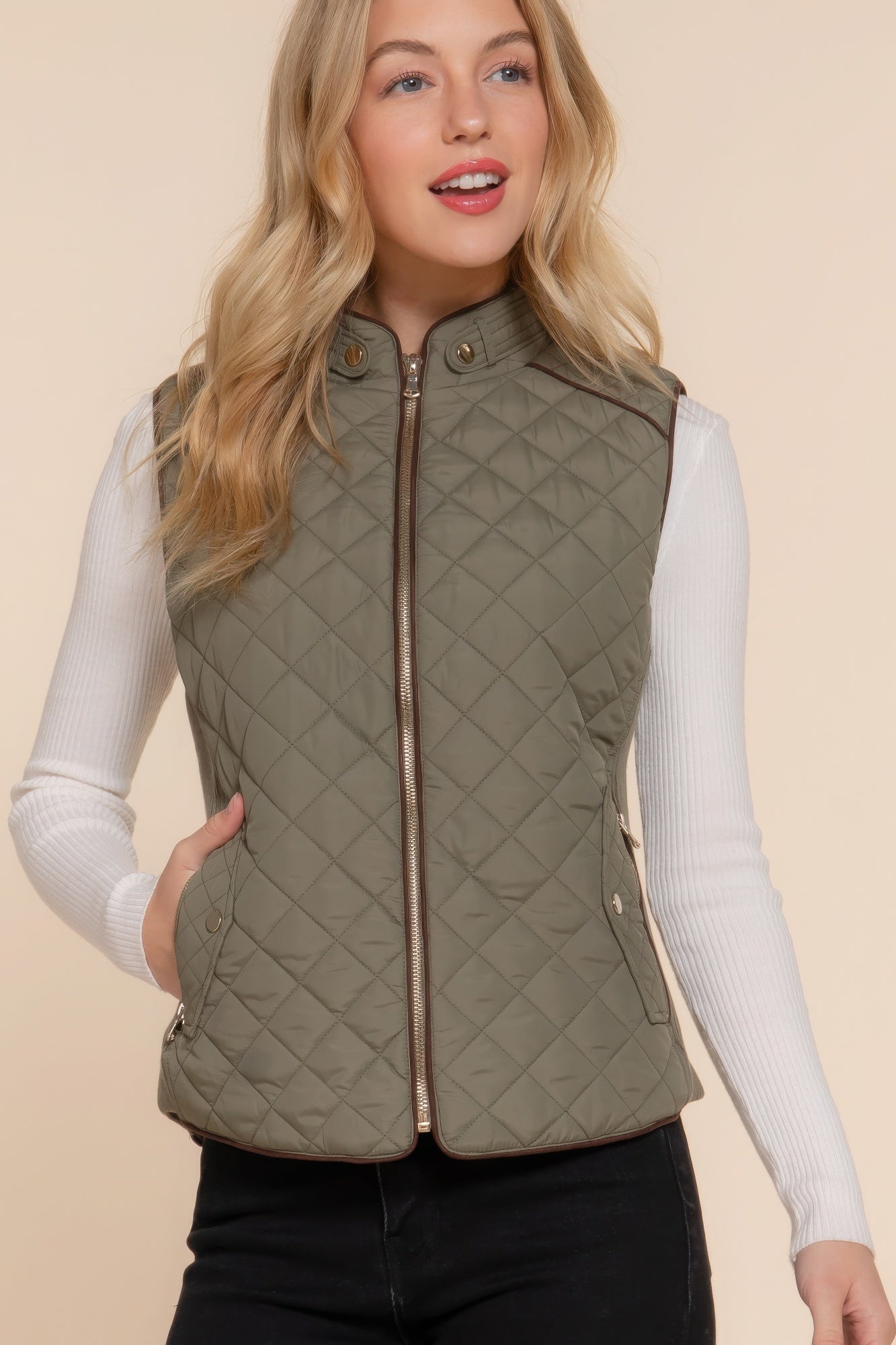 The Britney is our suede piping quilted padding vest. Crafted from 100% polyester, this vest is perfect for layering over sweaters or long sleeves. It features front pockets and side ribbing for added texture and style. Fabric: Made from 100% polyester. Colour: Olive.