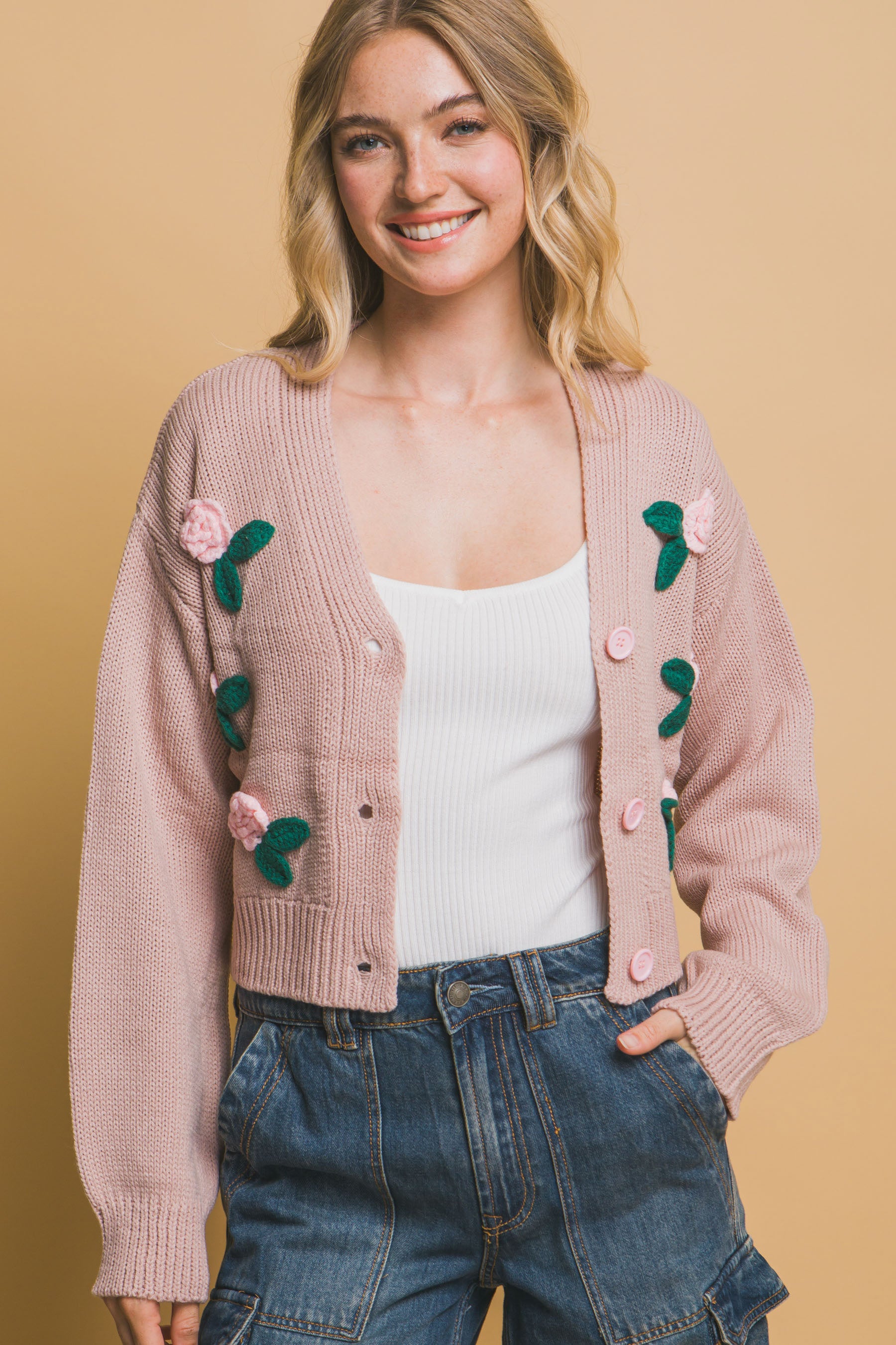 The Liya is a mid-cropped cardigan with charming flower details. Ideal for layering over dresses, blouses, or tees. Perfect for casual outings, work, or social events. Made from 100% acrylic. Colour: Pink Stone.